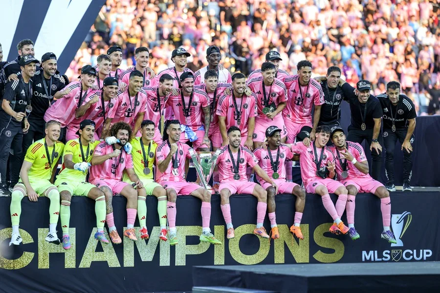 El legado de Lionel Messi ya estaba asegurado mucho antes de llegar al Inter Miami y unirse a la Major League Soccer (MLS). Había ganado una Copa del Mundo, decenas de trofeos y, en general, era considerado el mejor jugador en la historia del fútbol. No necesitaba una MLS Cup. Sin embargo, la quería, y la consiguió. Messi y el Inter Miami alcanzaron la cima, venciendo a los Vancouver Whitecaps 3-1 este sábado en la final de la MLS Cup, logrando el primer campeonato del club. Esto ocurrió dos años y medio después de la llegada de la leyenda al sur de Florida, un movimiento que sorprendió a muchos en su momento. “Decían que el fútbol nunca triunfaría en Estados Unidos”, dijo el comisionado de la MLS, Don Garber, durante la ceremonia de premiación. “Aficionados del Inter Miami, ¿ha triunfado el fútbol?” En el sur de Florida sí, gracias a Messi. Él asistió el gol que aseguró el título con un pase en el minuto 72 a Rodrigo De Paul, en una jugada donde Messi robó el balón y filtró un pase entre los defensores de Vancouver. De Paul la recibió en carrera, la mandó al rincón de la red y Messi saltó para abrazarlo unos segundos después, sonriente. Y mientras se agotaban los últimos minutos, los aficionados vestidos de rosa del Inter Miami —la mayoría con el número 10 de Messi en la espalda— se pusieron de pie y celebraron. El sur de Florida ya había visto títulos de la NFL, la NBA, la MLB y la NHL. Ahora también es una ciudad futbolera. Messi lo hizo posible. Tadeo Allende anotó en el minuto 6 del tiempo añadido —tras otra asistencia de Messi— para poner el 3-1. Y cuando Messi levantó el trofeo rodeado de sus compañeros, llovió confeti y estallaron fuegos artificiales. El Inter Miami se convirtió en la franquicia número 16 en la historia de la liga, de 30 años, en ganar un título de la MLS. Esto extiende una racha de paridad en la MLS, que ha visto a cinco franquicias diferentes ganar campeonatos en los últimos cinco años y a ocho franquicias reclamar un título en las últimas nueve temporadas; solo Columbus ha ganado dos veces en ese periodo. También fue la culminación de una odisea de 12 años para David Beckham, parte del grupo de propietarios del Inter Miami. Se retiró como jugador en 2013 y su contrato con la MLS le permitía iniciar una franquicia a tarifa reducida al terminar su carrera. Beckham eligió Miami y le tomó años hacerlo realidad; no fue hasta enero de 2018 cuando el club nació formalmente, tras asociarse con los empresarios Jorge Mas y Jose Mas, y aun así el equipo no tenía un estadio definido. El equipo comenzó a jugar en 2020, y Messi llegó a mitad de la temporada 2023. En ese momento, el Inter Miami estaba en el último lugar de la MLS. Y entonces llegó Messi. El equipo que era último, ahora lidera la liga. “Ha sido un viaje increíble”, dijo Beckham. El trofeo es el número 47 de Messi entre clubes y selección, extendiendo su récord global en el fútbol masculino, y algunos dicen que en realidad es el 48 porque la MLS otorga un trofeo por ganar el título de conferencia también. Ahora ha ganado al menos 21 títulos en finales a partido único, muchos de ellos con el núcleo de este equipo: Sergio Busquets, Jordi Alba, Luis Suárez y Javier Mascherano, sus compañeros de siempre en el Barcelona. Busquets y Alba se retiran y pudieron despedirse como campeones. El futuro de Suárez es incierto. Mascherano es ahora el entrenador, quien cambió la alineación y táctica del Inter Miami a mitad de temporada —su primera dirigiendo el club— con este momento en mente. Y el Messi de 38 años, el Jugador Más Valioso (MVP) de la MLS 2024 que parece seguro para ganar el premio otra vez esta temporada, sigue siendo único en los momentos más importantes y con un contrato que podría mantenerlo jugando en Miami hasta pasados los 40 años. Cuando comience la próxima temporada, el equipo jugará en un estadio nuevo cerca del Aeropuerto Internacional de Miami, con la mira puesta en un título consecutivo. “No está aquí solo para disfrutar de vivir en Miami”, dijo Beckham. “Su esposa y los niños aman Miami, pero él ha venido aquí para ganar, y de eso se trata realmente Leo. Quiere ganar. Tiene esa dedicación, la lealtad que muestra a sus compañeros, a la ciudad, al club. Leo es un ganador. Es así de simple”. Inter Miami se adelantó 1-0 con un autogol en el minuto ocho, antes de que Vancouver empatara en el minuto 60 con un gol de Ali Ahmed. Otro disparo de Vancouver pegó en ambos postes cerca de dos minutos después, pero no entró, y el Inter Miami recuperó la ventaja de forma definitiva cuando Messi encontró a De Paul. Y poco después del silbatazo final, Messi fue hacia la sección de aficionados del Inter Miami y levantó ambas manos en el aire. Fue un momento que se gestó durante dos años y medio.